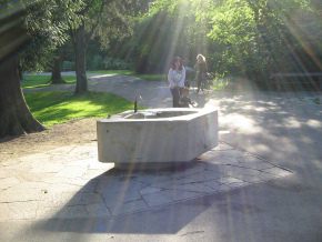 Sch�tzenmattpark, ein Vogel (Spatz) sitzt auf
                      dem Brunnenrand, und eine Frau kommt mit einem
                      Kind