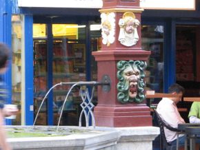 Basel, Steinenvorstadt,
                                Webern-Brunnen, Brunnenstock mit Masken
                                und Wasserrohren