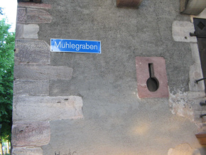 Basel, Sankt-Alban-Rheinweg,
                                Stadtmauer, Strassenschild
                                "M�hlegraben" am Glockenhaus,
                                und eine Schiessscharte