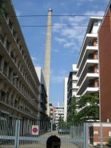 Chemie-Terror 46: Mattenstrasse, Sicht auf
                        den grauen Kamin der Chemie-Giftfabrik Syngenta
                        von einem weiteren Eingang aus