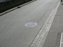 Kanalisationsterror, Stink-Dolendeckel 08
                        an der Tramstation "Heuwaage". Hier
                        sieht man die Stink-Dolendeckel in der Fahrbahn,
                        Nahaufnahme. W�h, das stinkt!