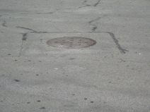 Kanalisationsterror, Stink-Dolendeckel 11
                        an der Kreuzung Marktplatz / Eisengasse,
                        Nahaufnahme. W�h, das stinkt!