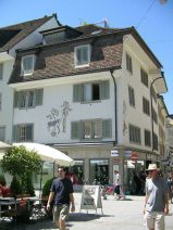 Winterthur: Neumarkt, bemaltes Eckhaus mit
                        Motiv einer Frau, die von einem Baum erntet, und
                        einem Esel, der danebensteht