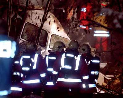 Polizei mit Leuchtstreifen stehen um das
                        Cockpit im Wald