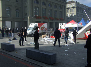 Federal Square of Berne with
                            overthrown tables and racist SVP propaganda
                            material on the floor, October 6, 2007