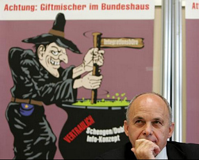 Ueli
                            Maurer vor dem Giftmischerplakat gegen das
                            Schengen-Abkommen im Oktober 2004